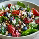 Fresh baby spinach and juicy mixed berries tossed with creamy goat cheese and crunchy toasted walnuts in a vibrant bowl. 