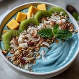 Vibrant blue spirulina smoothie bowl topped with colorful tropical fruits for breakfast.