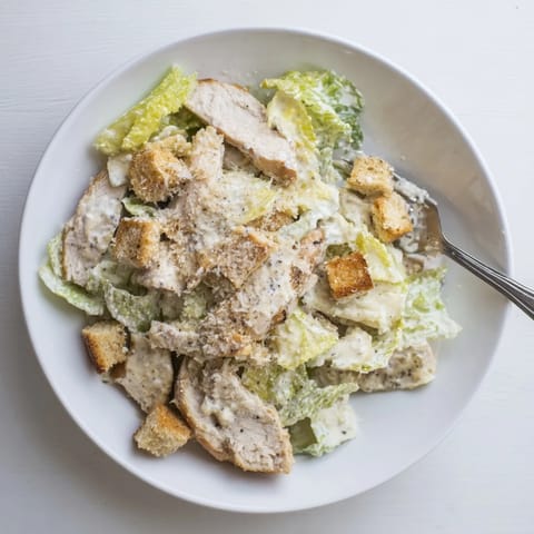 Juicy grilled chicken crowns a vibrant bowl of romaine tossed in rich Caesar dressing, with golden croutons and Parmesan shavings.