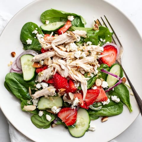Fork-tender shredded chicken mingles with juicy strawberries, crunchy cucumber, and feta in a light poppy seed dressing for an easy, gluten-free main course salad.