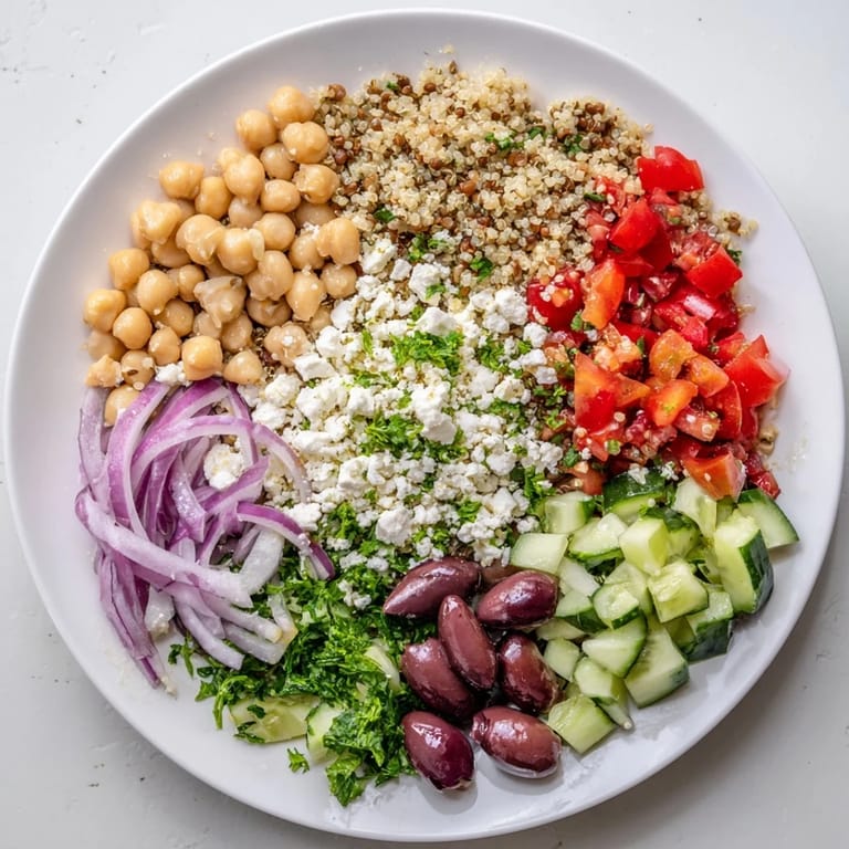 Sunlit Greek Power Salad topped with Kalamata olives, red onion, and fresh parsley, drizzled with vinaigrette.