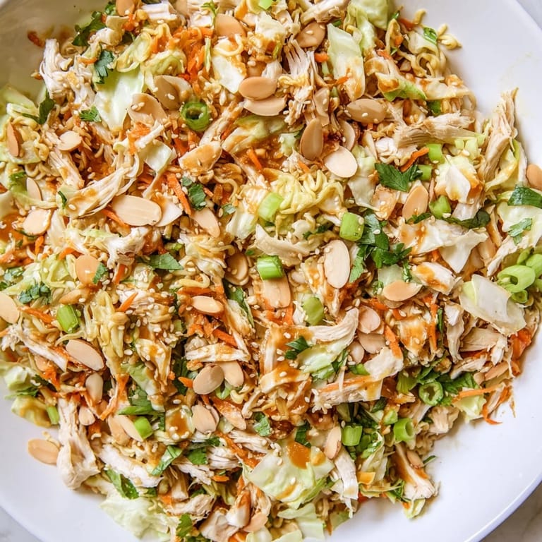 Colorful Crunchy Ramen Chicken Salad served in a bowl, garnished with cilantro and sesame seeds, showcasing its crisp textures and appetizing look.