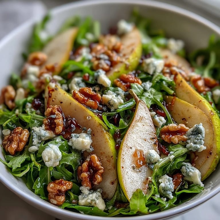 A light and healthy Arugula and Pear Bowl served on a white plate with a glass of crisp white wine nearby.