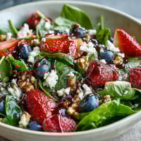 Fresh baby spinach and juicy mixed berries tossed with creamy goat cheese and crunchy toasted walnuts in a vibrant bowl. 