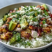 Vibrant Cauliflower Rice Bowl with seasoned chicken, crisp broccoli, and creamy avocado slices.